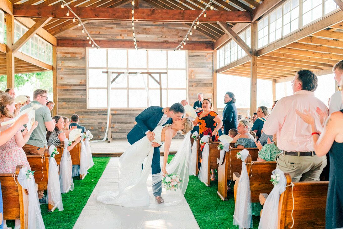 Couple kissing in the aisle as guests look on