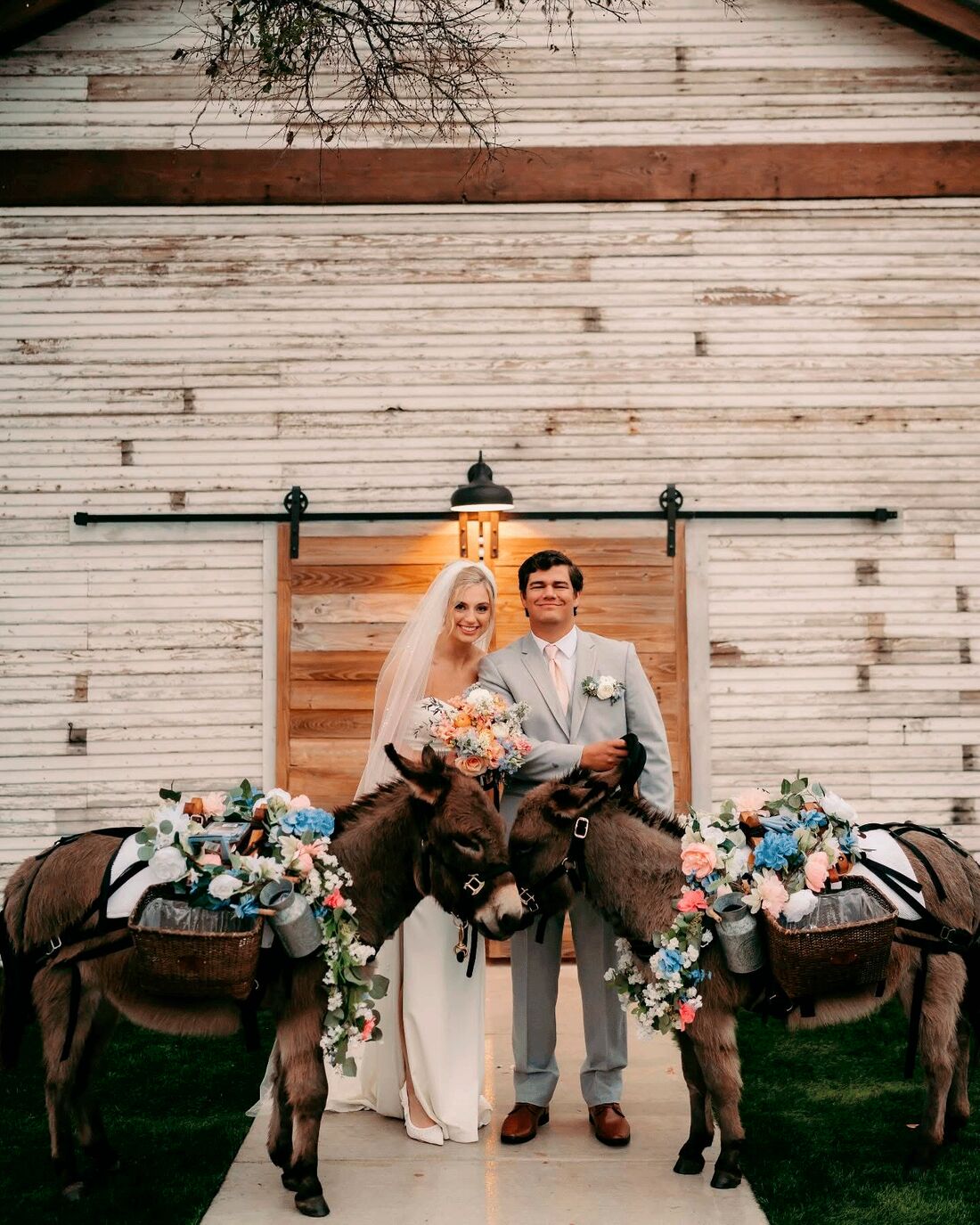 Couple standing at the chapel doors with two flower-dressed donkeys
